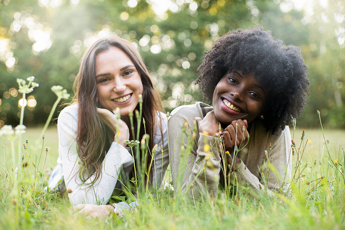 Portrait of smiling young female friends lying in park