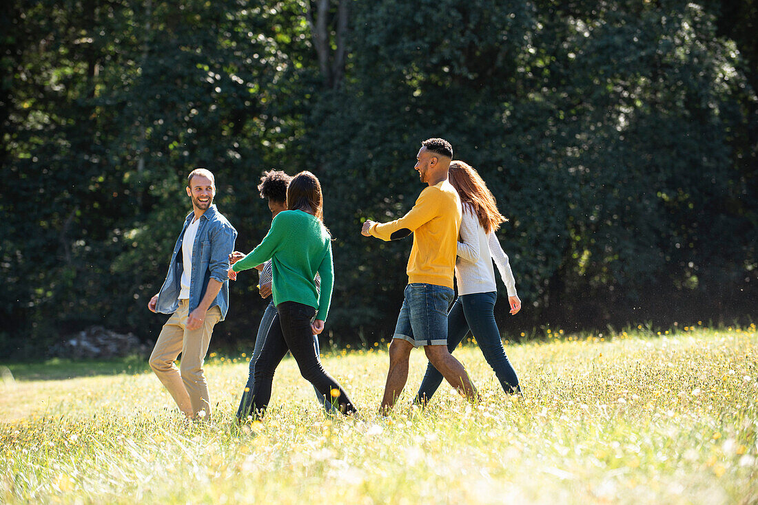 Glückliche junge Freunde, die zusammen in einem öffentlichen Park spazieren gehen