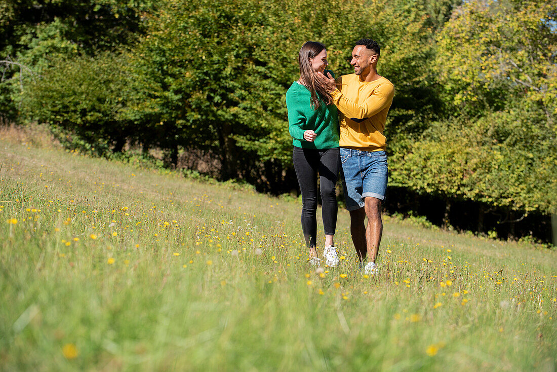 Smiling young couple looking at each other in public park