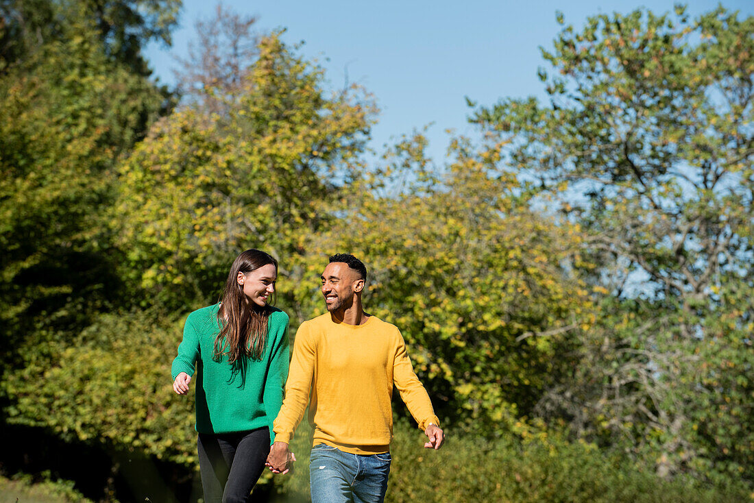 Smiling young couple walking in public park