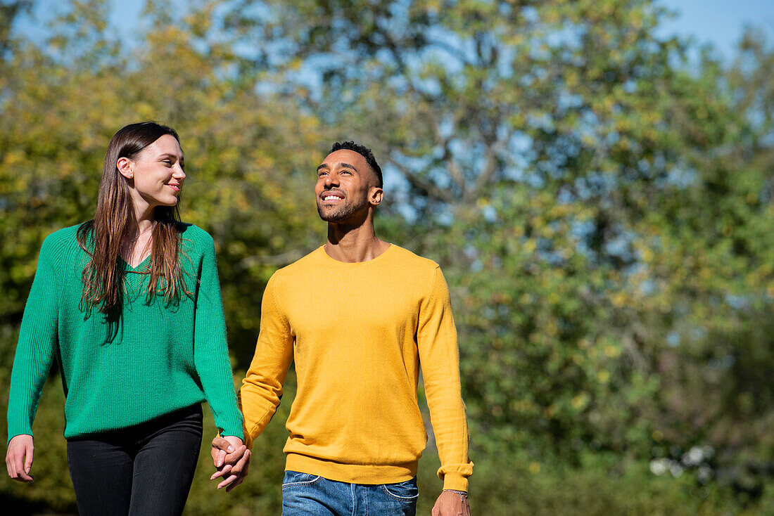 Smiling young couple walking together in public park