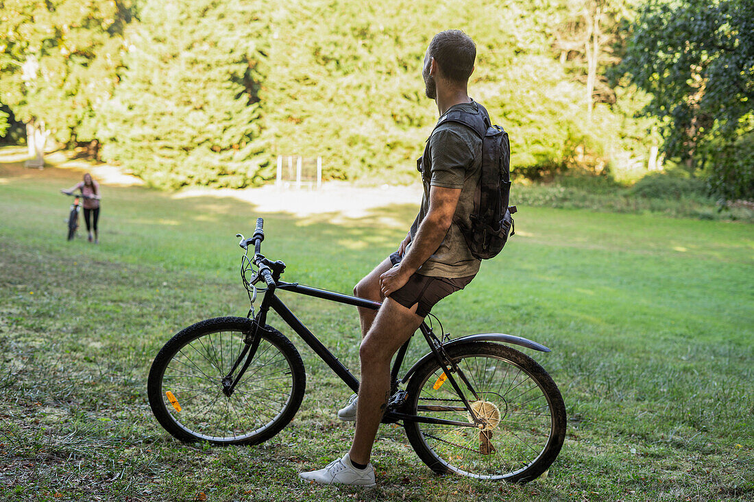 Young man sitting on bicycle while relaxing in forest
