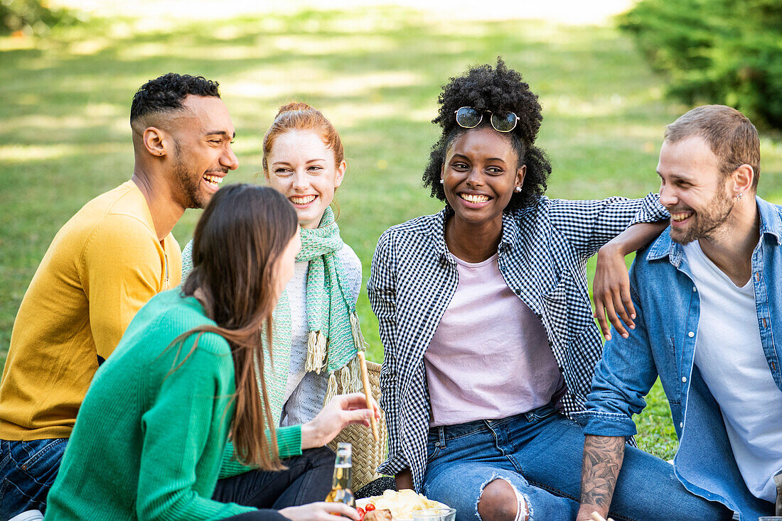 Glückliche junge Freunde beim Picknick im öffentlichen Park