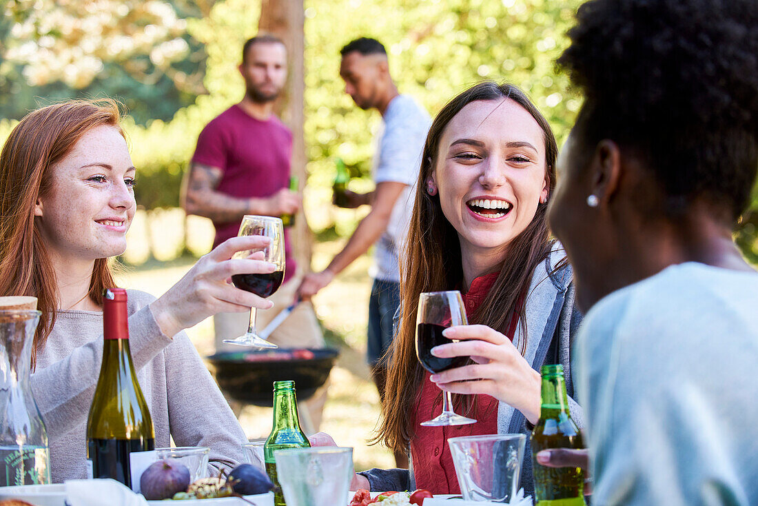 Lächelnde junge Frauen bei Wein und Bier im Park