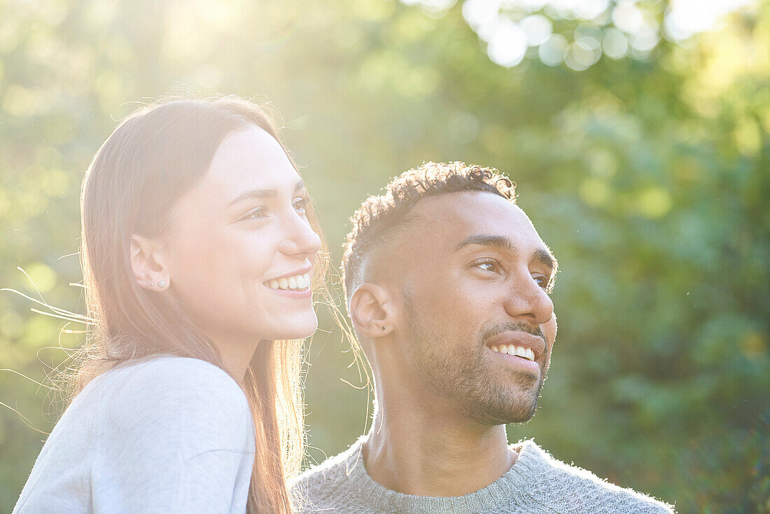 Close-up of smiling young couple looking away in public park