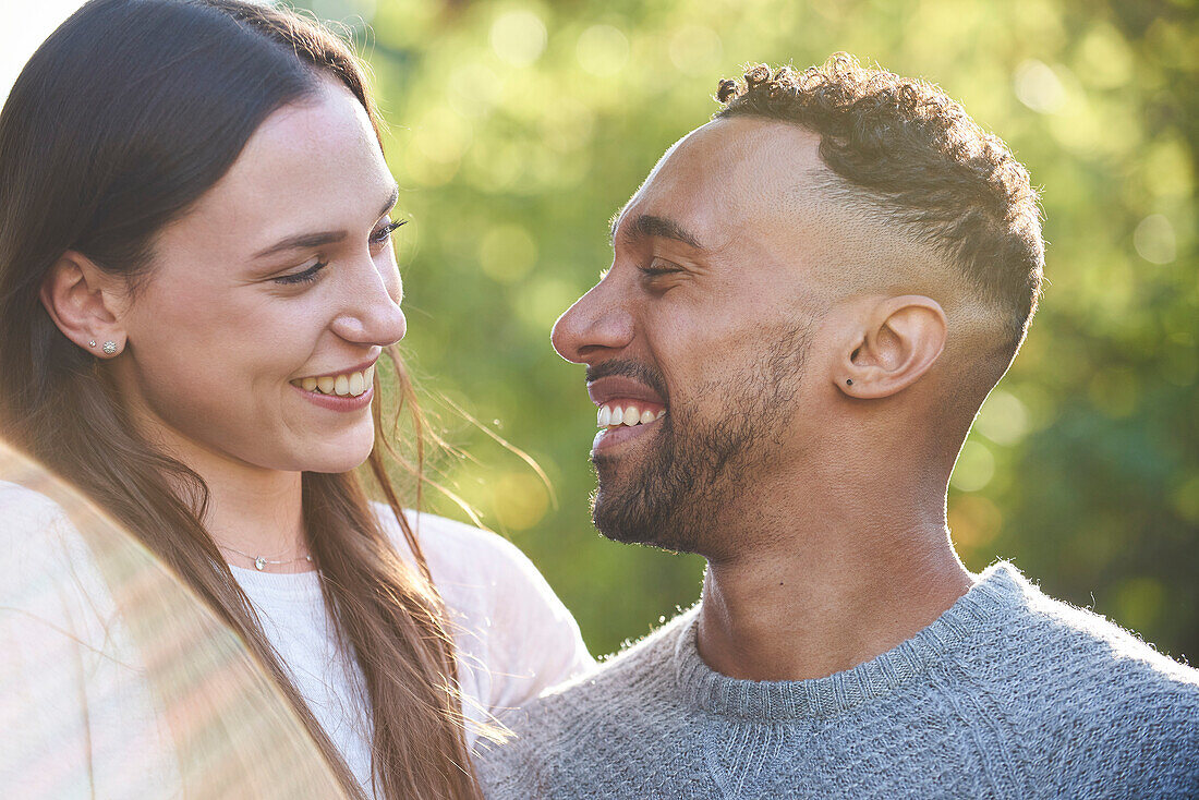 Close-up of smiling young couple looking at each other in public park