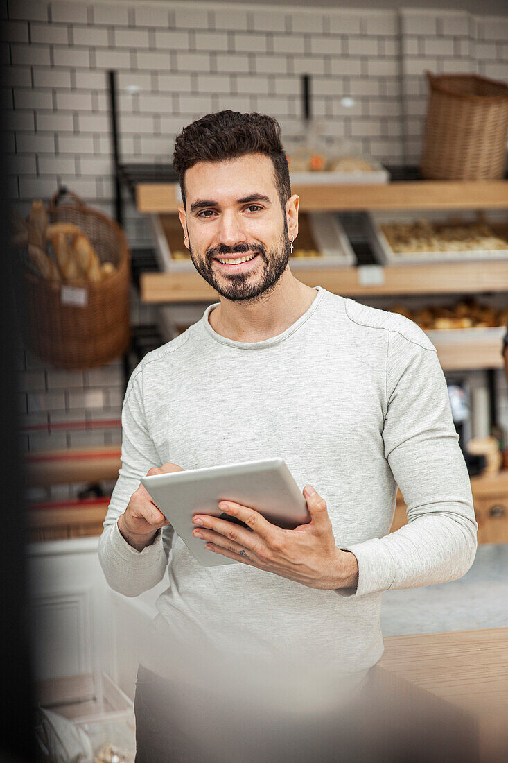 Bakery owner holding digital tablet while looking at the camera