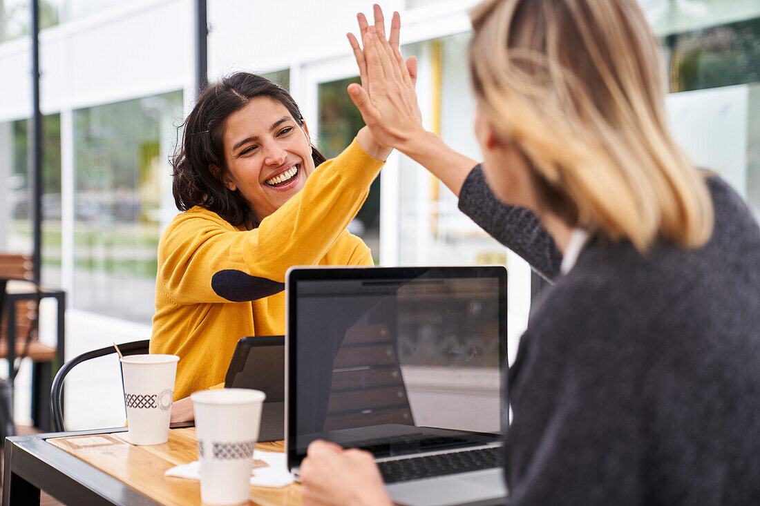 Shot of two female work mates high-fiving each other while working outdoors