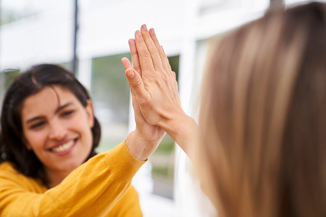 Shot of Latin-American businesswoman high-fiving her co-worker in outdoors office