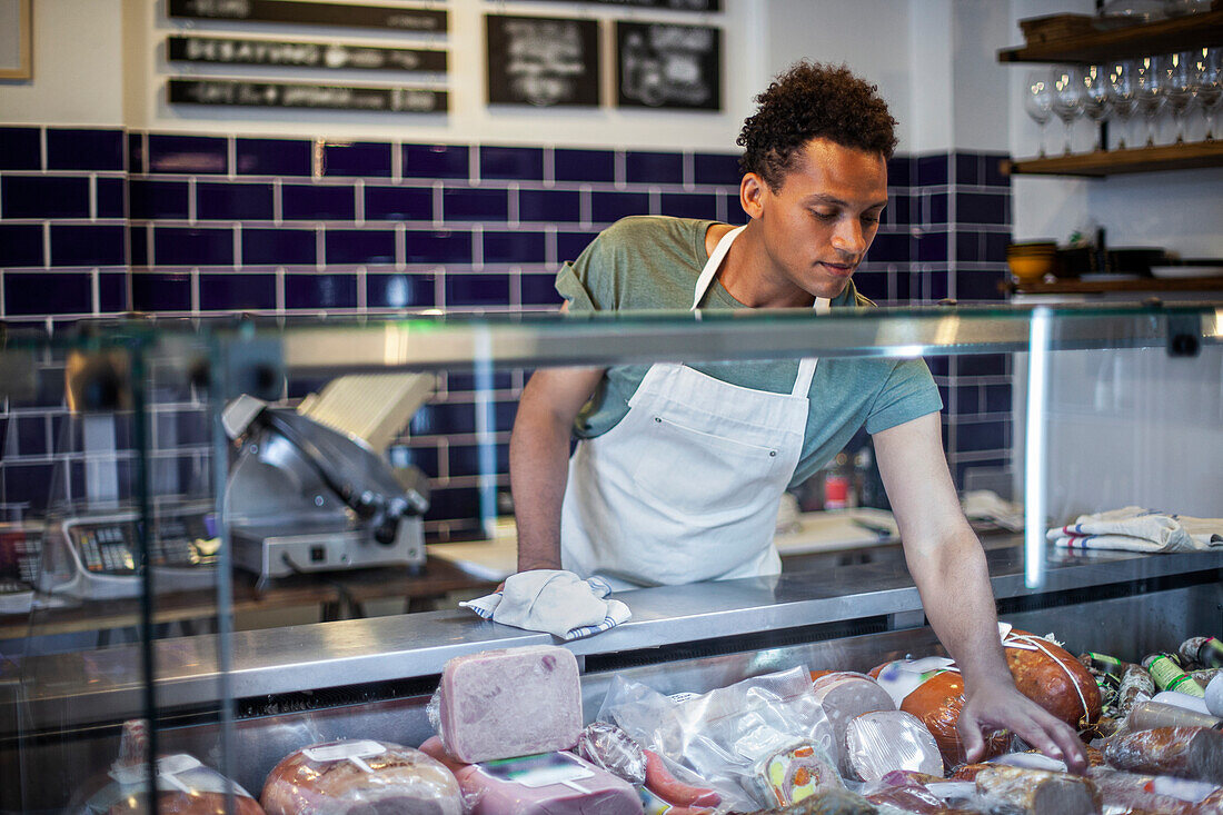 Latin American grocery store worker organizing packed food in refrigerator