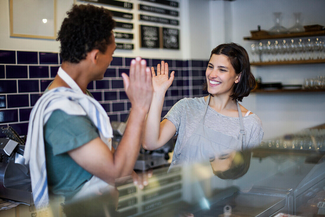 Grocery store female worker high fiving with male colleague