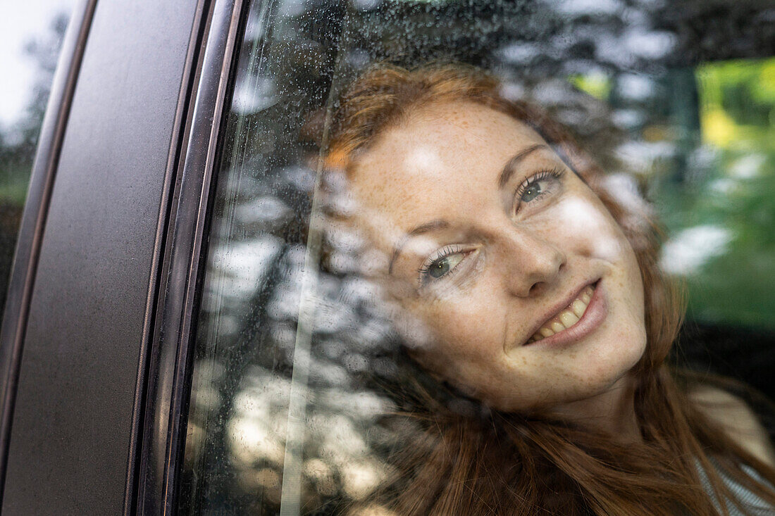 Lächelnde junge Frau im Auto sitzend