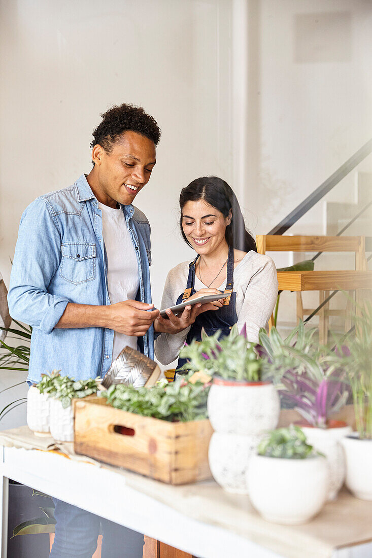 Small business plant shop coworkers looking at digital tablet