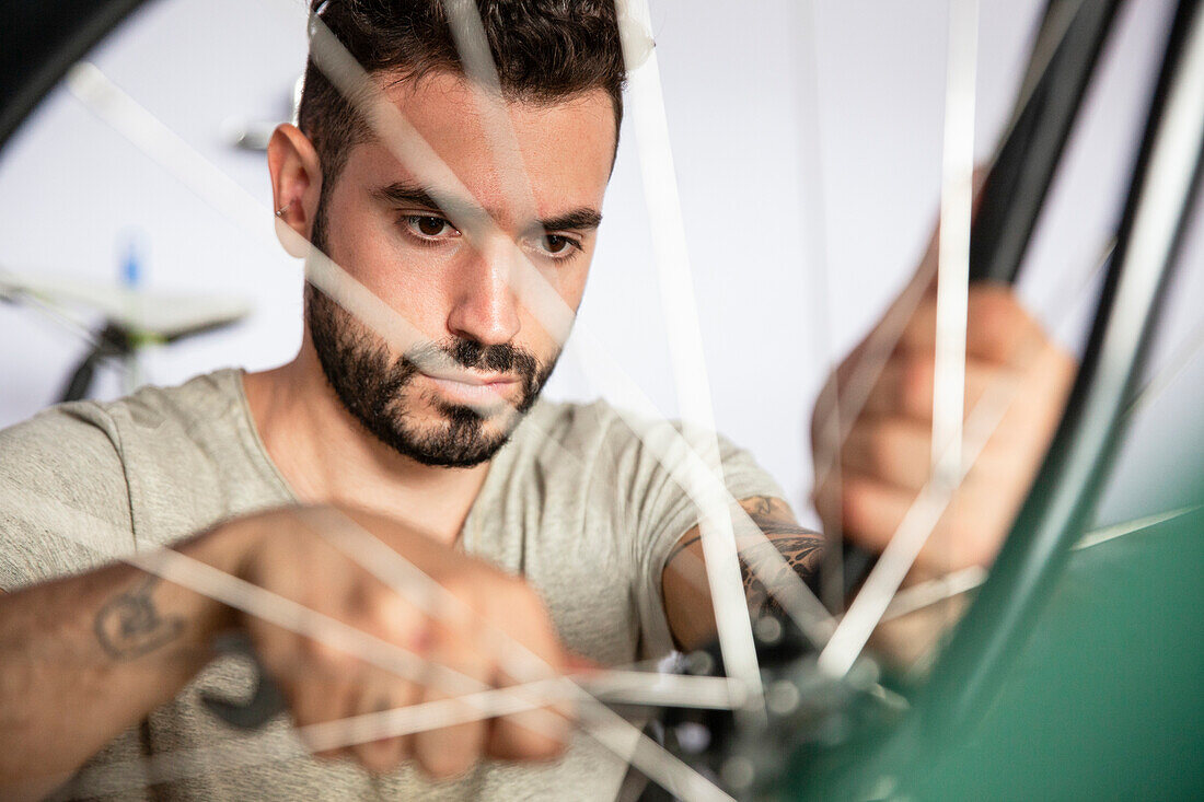 Young adult mechanic reparing bicycle wheel