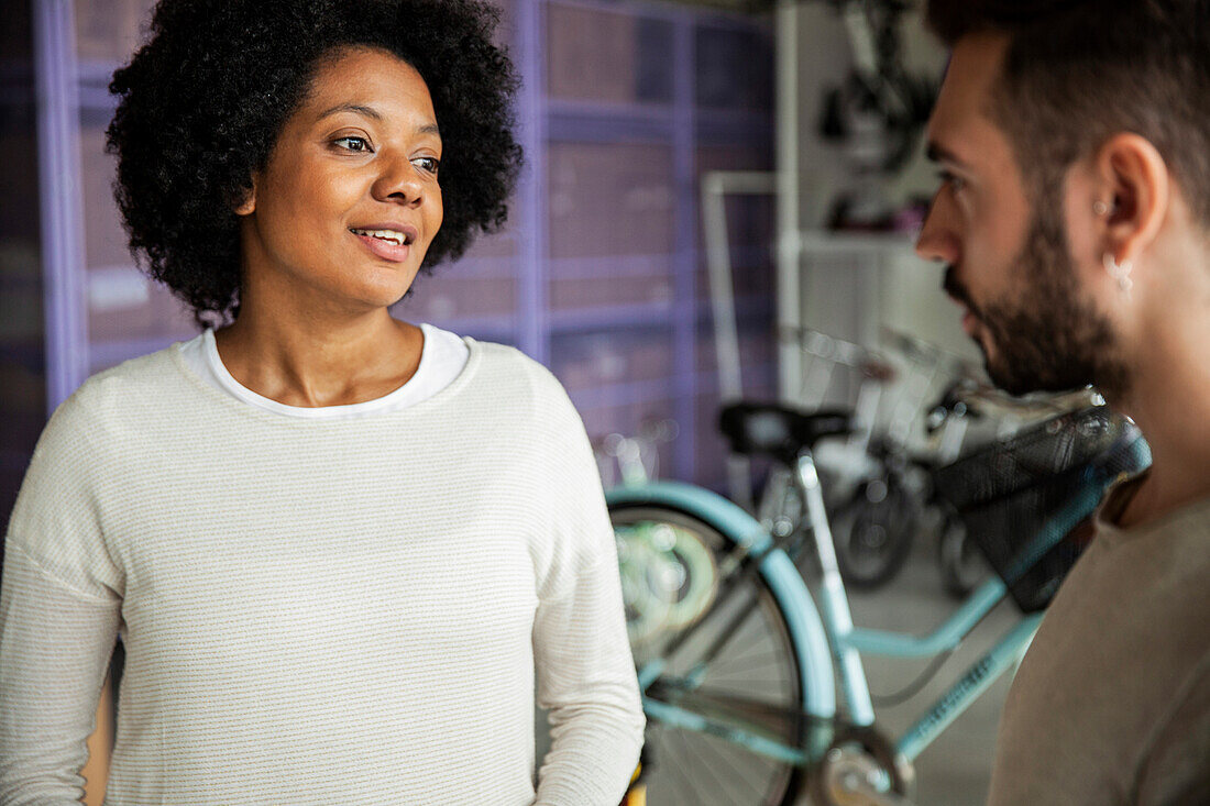 Afroamerikanische Frau im Gespräch mit dem Inhaber eines Fahrradgeschäfts