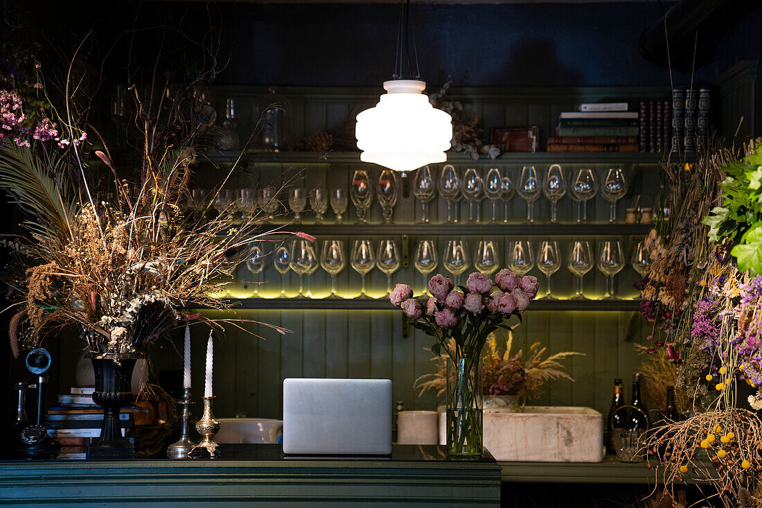 Low key shot of a wine bar decorated with variety of dried flowers bouquets and vases