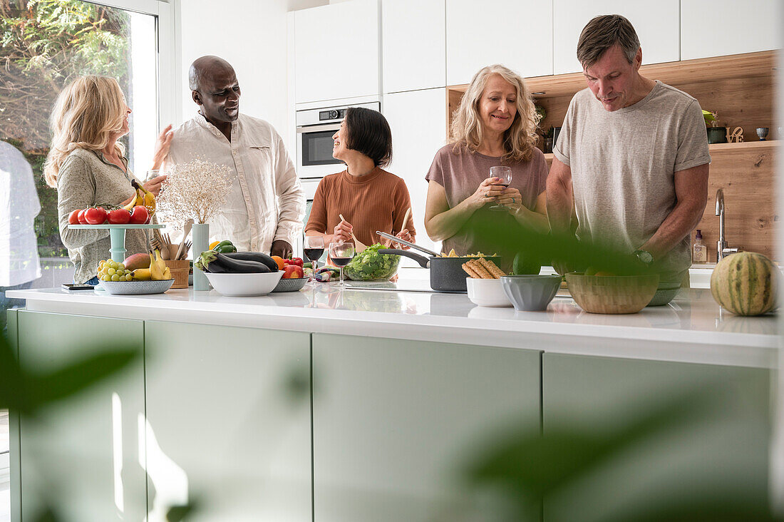 Diverse group of friends having a good time in the kitchen while getting ready to eat