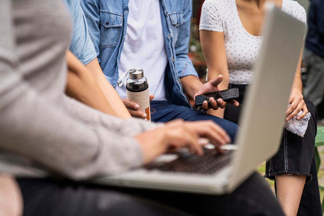 Close-up shot of several people's hands holding smartphones and laptop computer