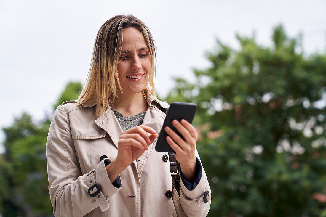 Attraktive Frau schaut auf ihr Handy, während sie auf der Straße geht