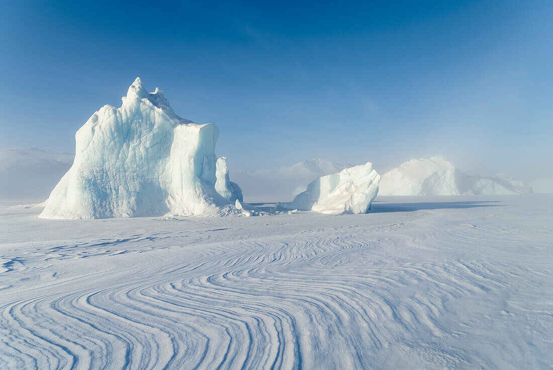 Icebergs frozen into the sea ice of the Uummannaq Fjord System during winter. Background is Nuussuaq Peninsula, Greenland, Denmark.