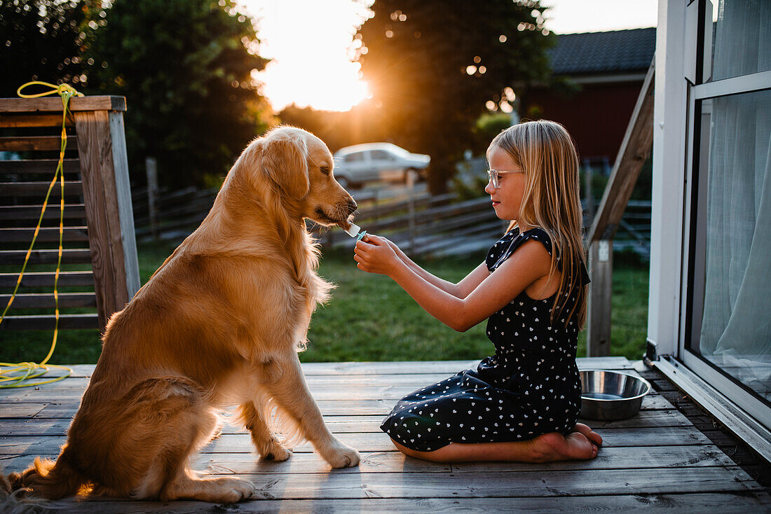 Girl giving dog ice loll