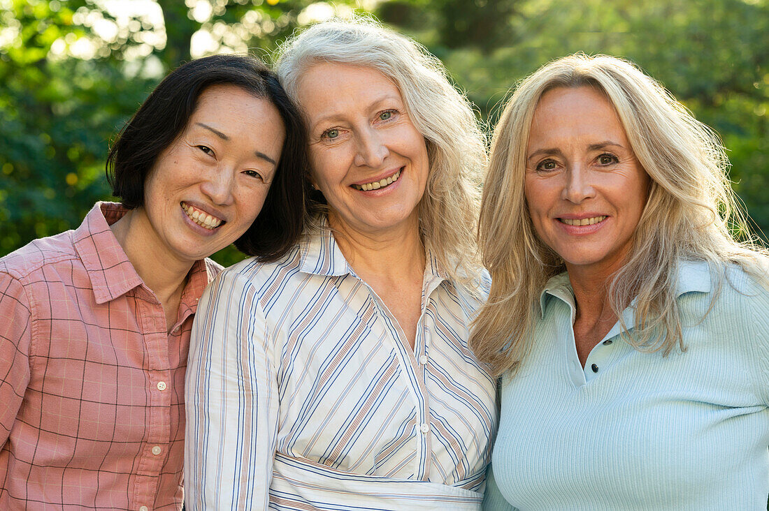 Drei ältere Frauen posieren zusammen für ein Gruppenfoto im Freien