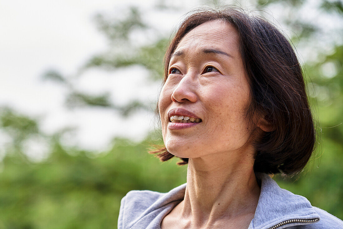 Senior Asian woman looking up while standing outdoors