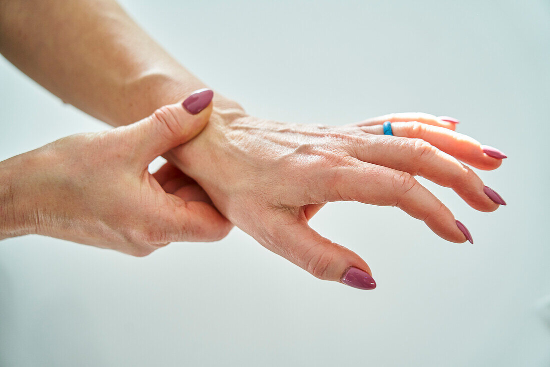 Ältere Frau hält ihr Handgelenk, während sie ihren Puls fühlt