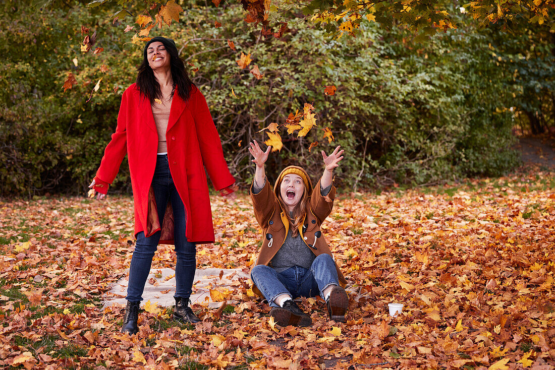 Friends playing with autumn leaves in park