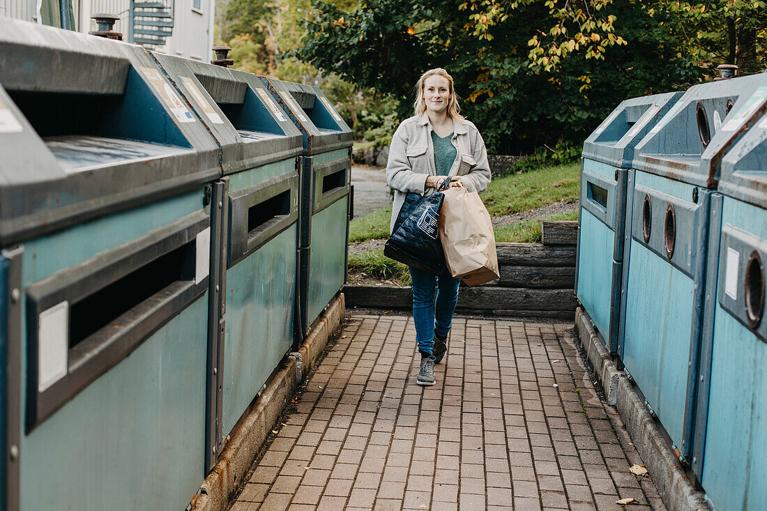 Frau trägt Papiersäcke mit Recyclingmaterial