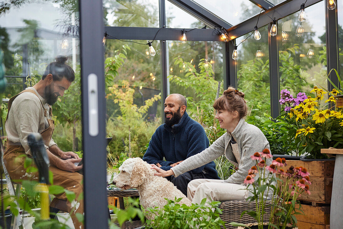 Smiling friends sitting in greenhouse