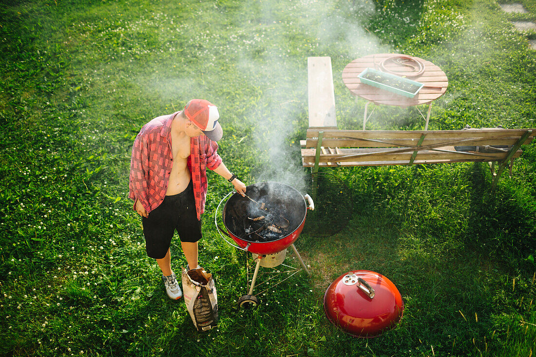 Mann bereitet Grill im Garten vor