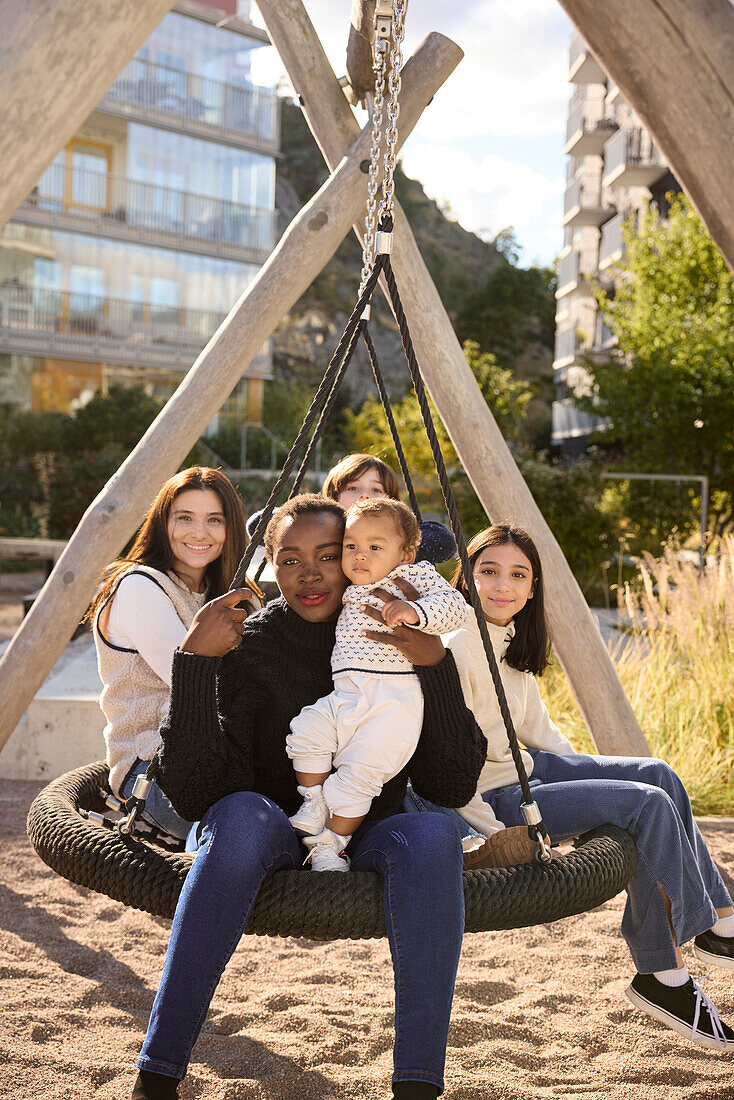 Frauen mit Kindern auf einer Schaukel sitzend