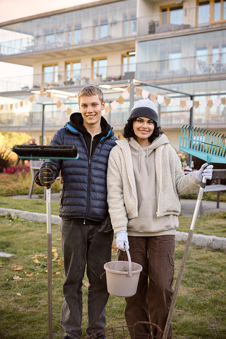 Young people holding garden tools