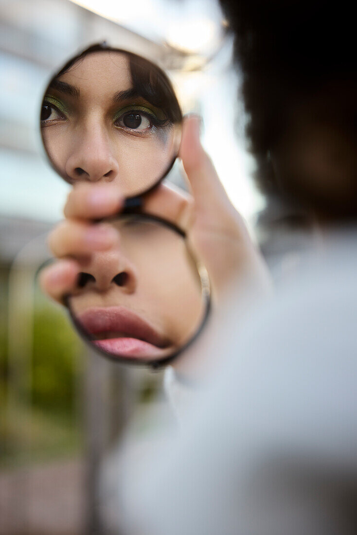 Young woman reflecting in hand mirror