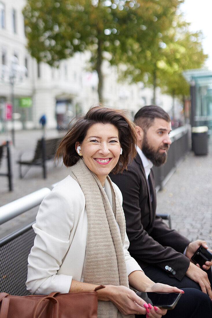 Smiling colleagues sitting on bench