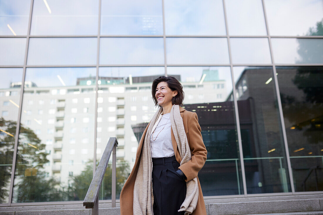 Lächelnde Geschäftsfrau vor einem Bürogebäude