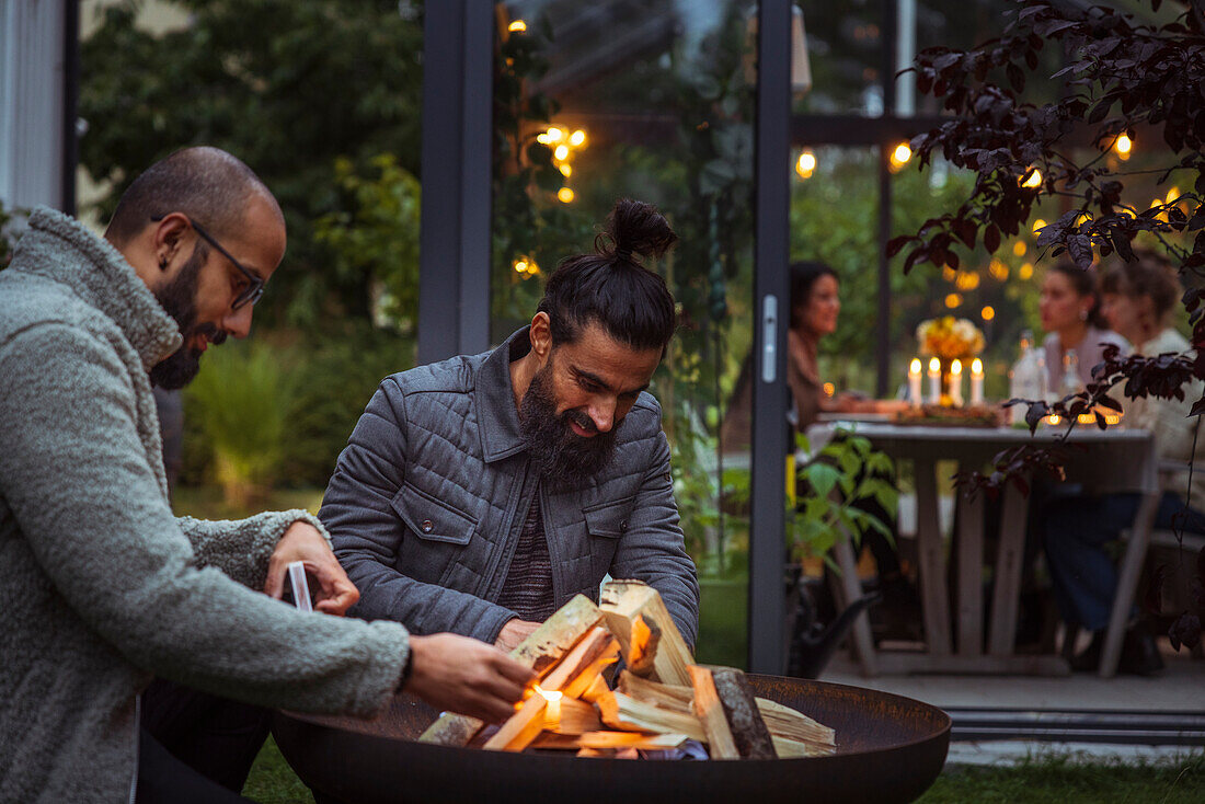 Male friends preparing fire in garden