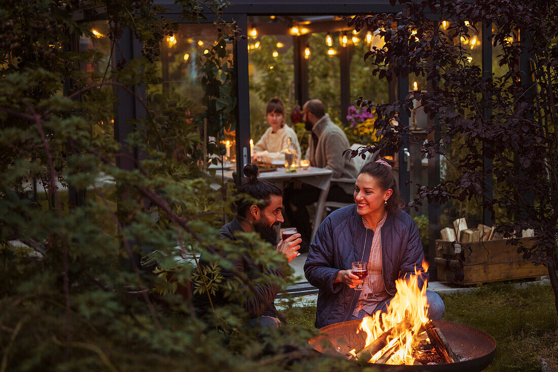 Freunde sitzen am Feuer im Garten