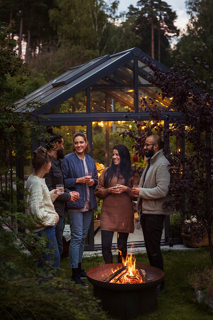 Freunde stehen am Feuer im Garten