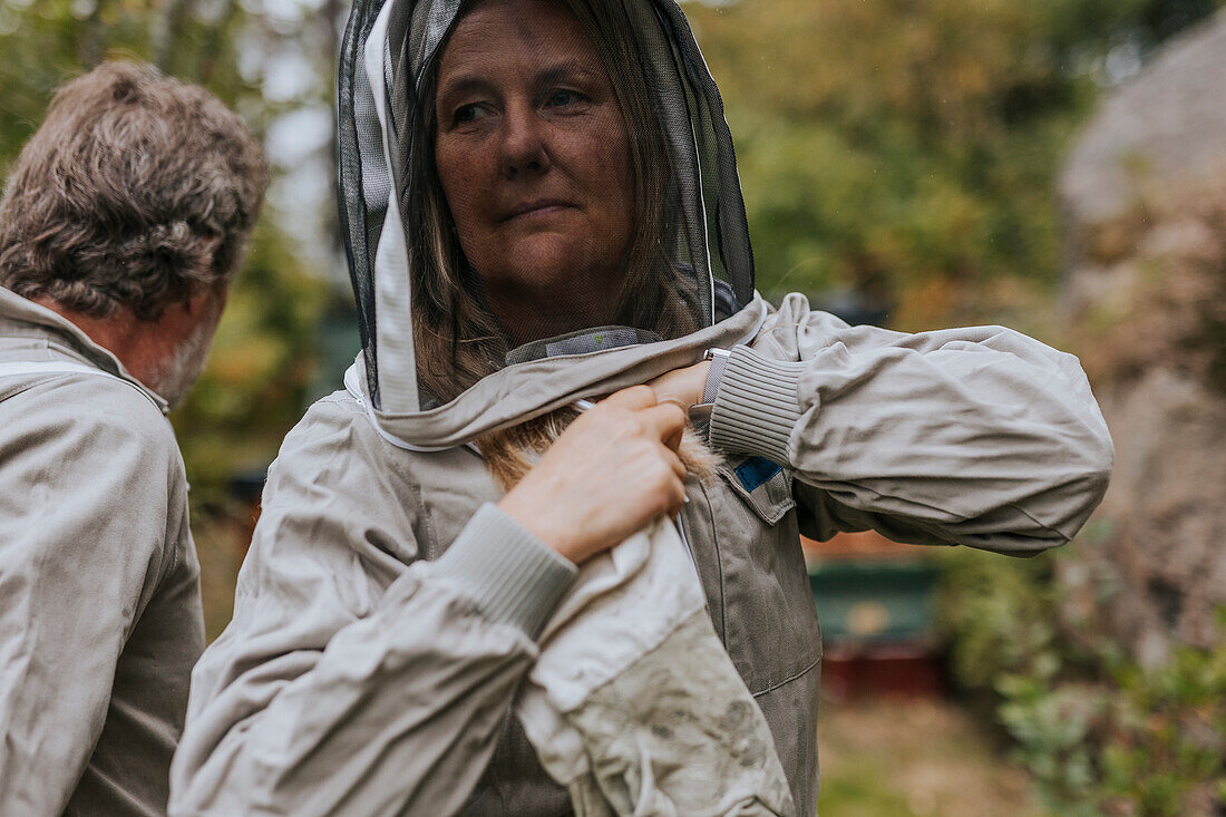 Woman putting beekeepers suit on