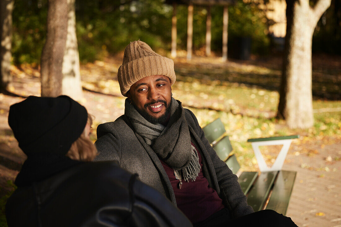 Smiling man talking to friend on bench