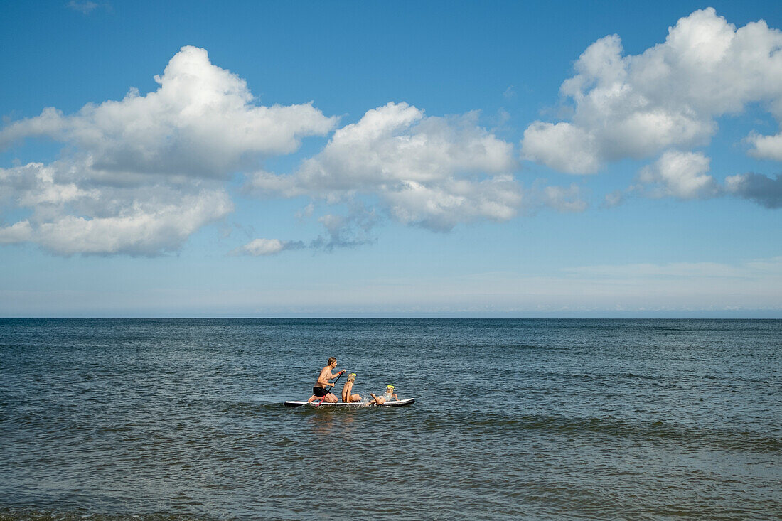Father with kids paddleboarding on sea