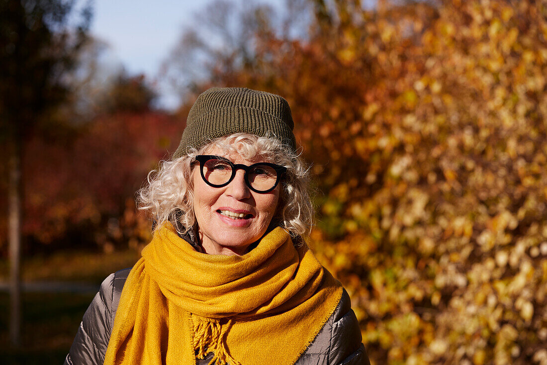 Porträt einer älteren Frau in einer Herbstlandschaft