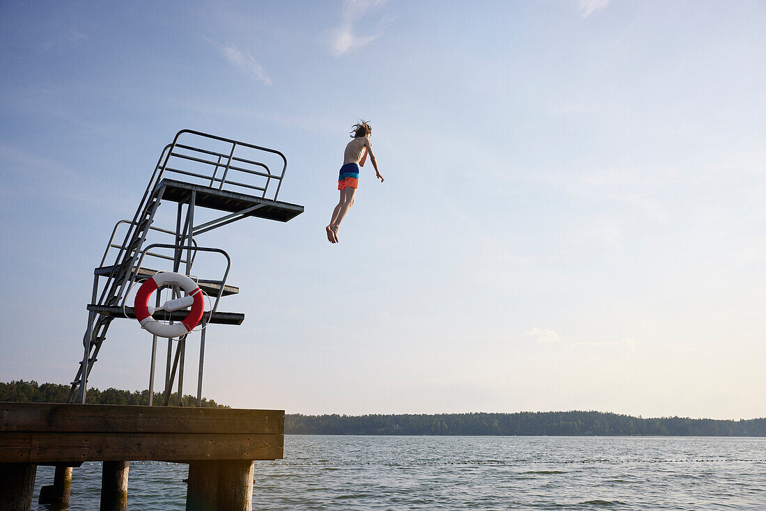 Teenage boy jumping into water from jumping tower