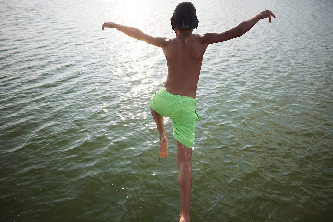 Teenage boy jumping into water