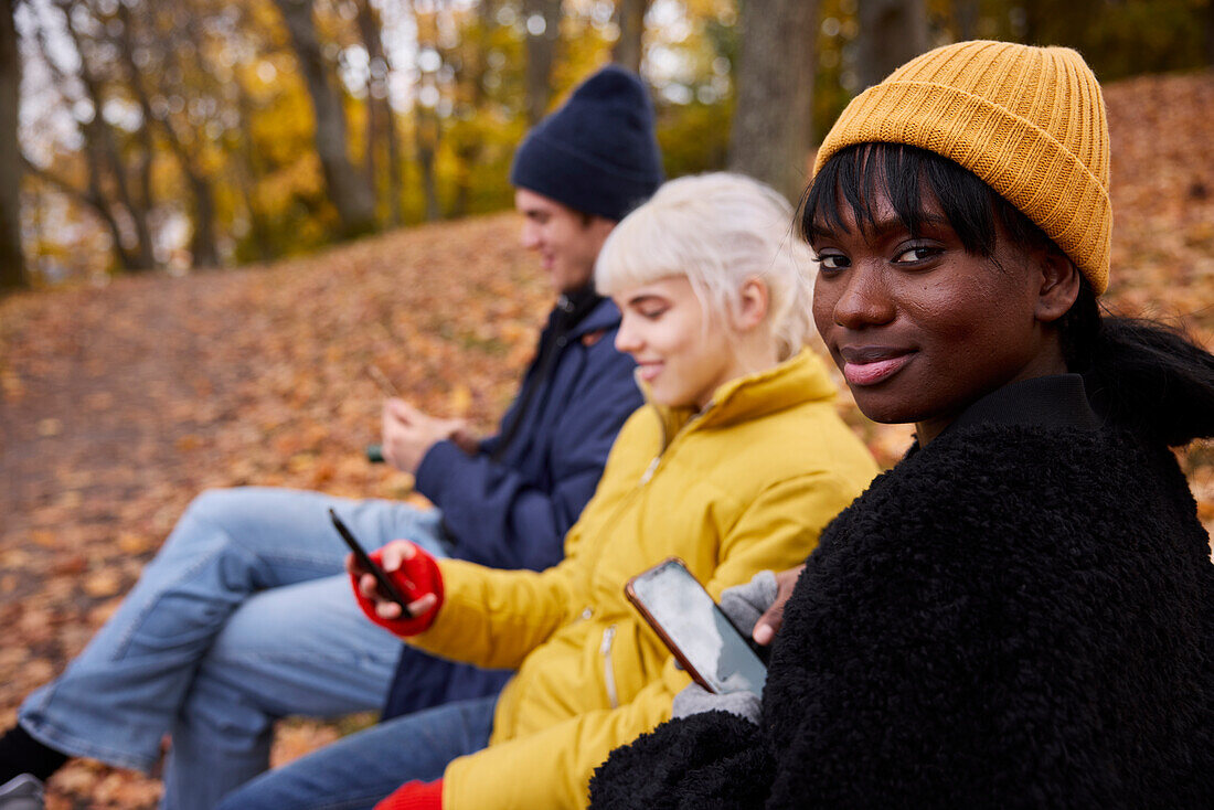 Three friends in park using smartphones