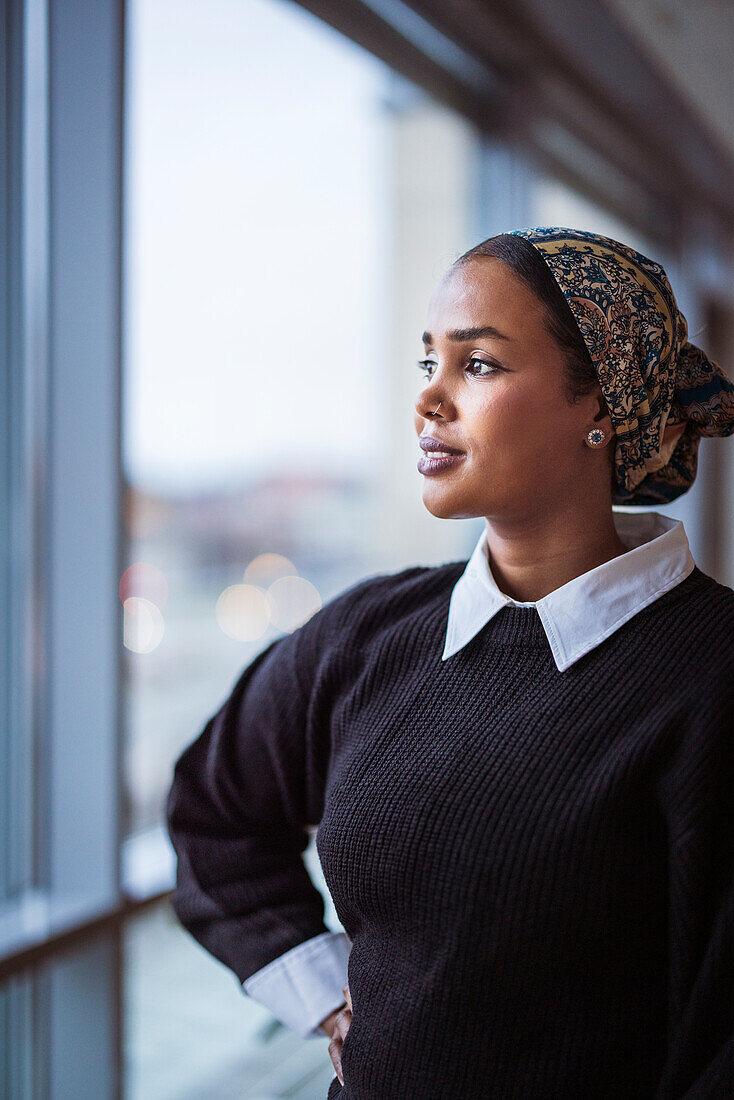 Young woman looking through window