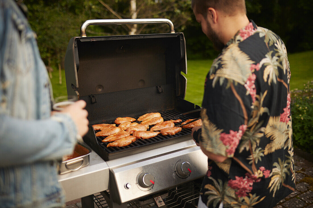 Mann bereitet Fleisch auf dem Grill zu