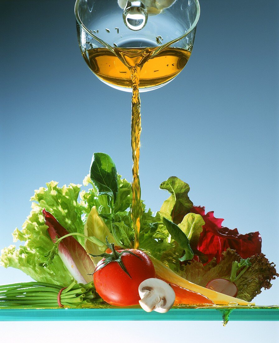 Kräuteröl wird auf gemischten Salat gegossen